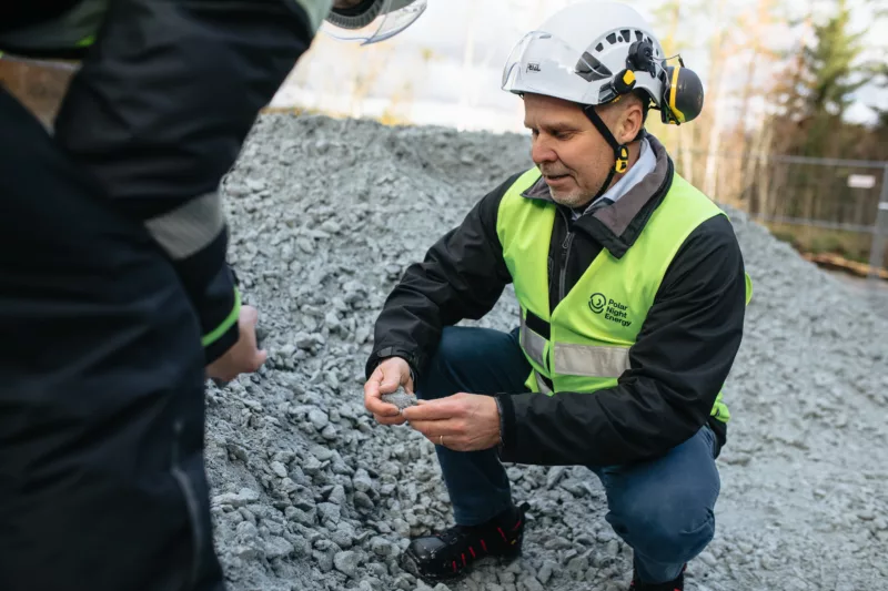 A person inspecting crushed soapstone.